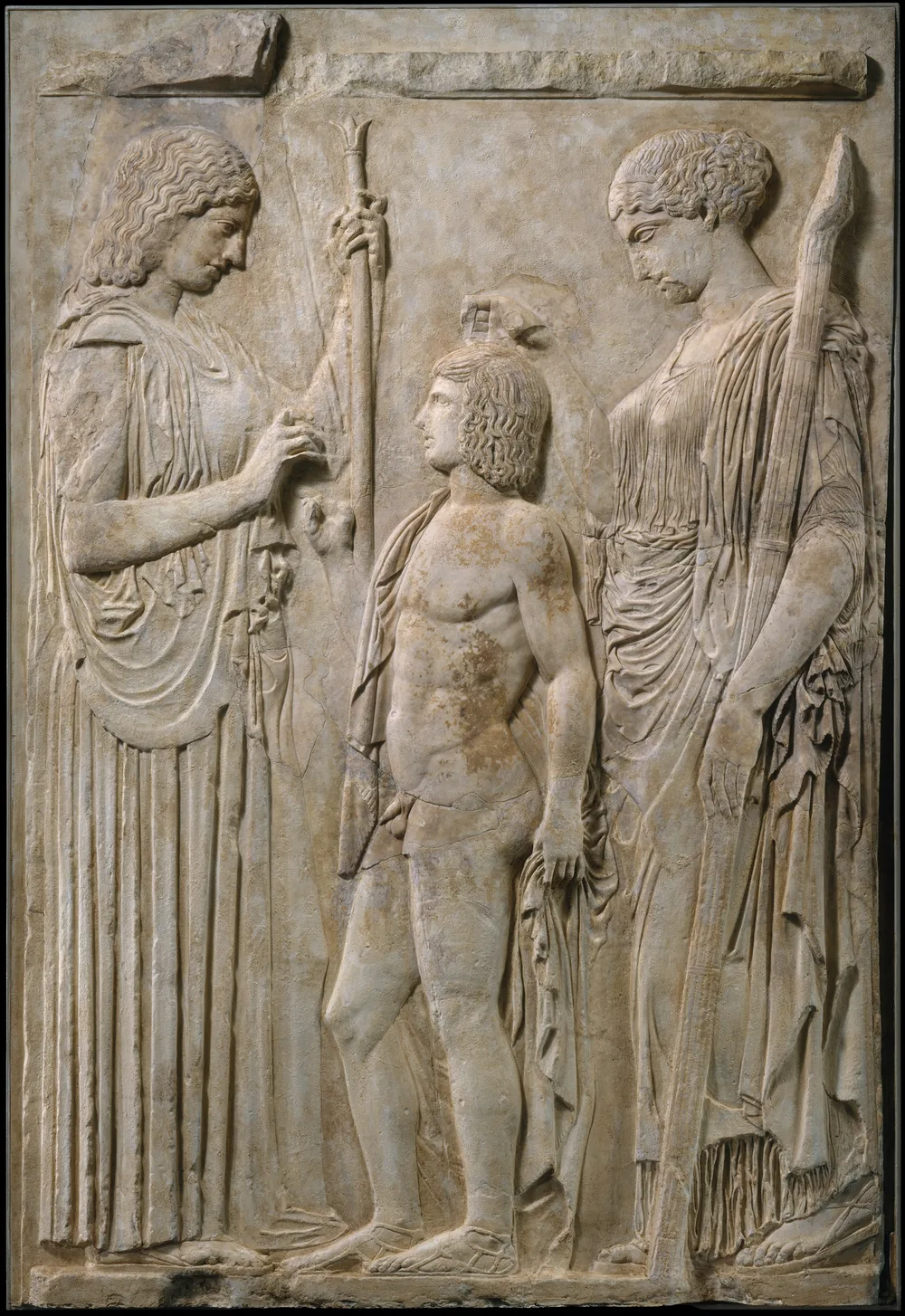 The complete Eleusinian relief shows Demeter with a scepter on the left and Persephone with a torch on the right. A youth usually identified as Triptolemos stands between them. Ancient marble fragments are set into a cast.